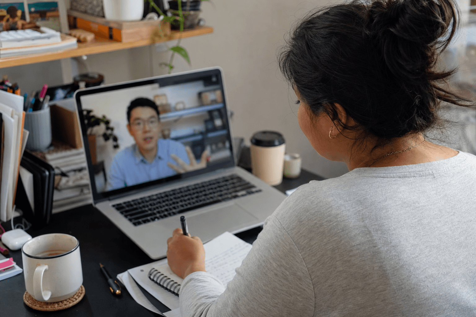 A solo founder on a video call taking notes while a potential customer explains a workflow problem on screen