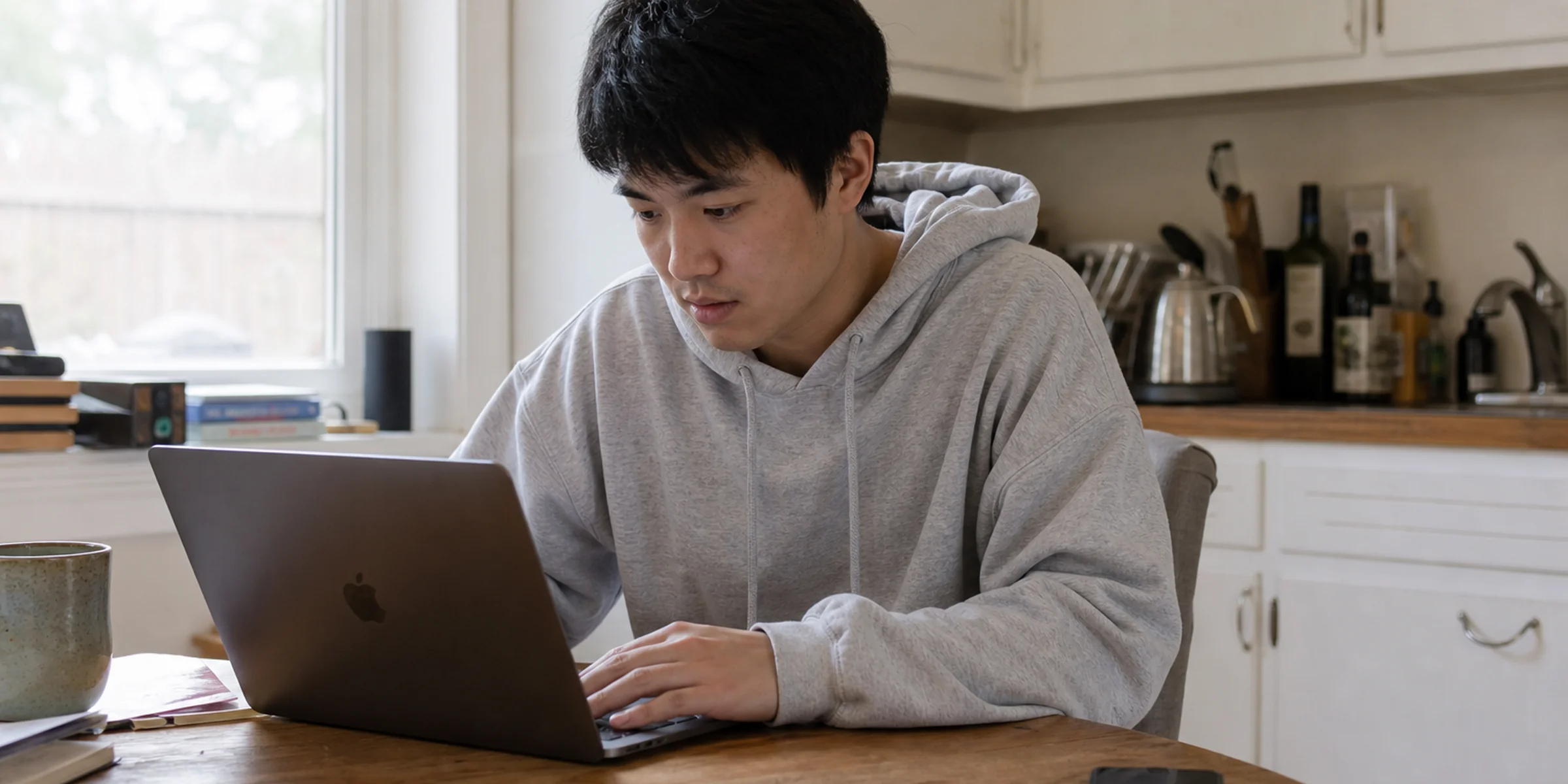 East Asian founder at a kitchen table drafting onboarding emails with sticky notes labeled day 1 through day 3
