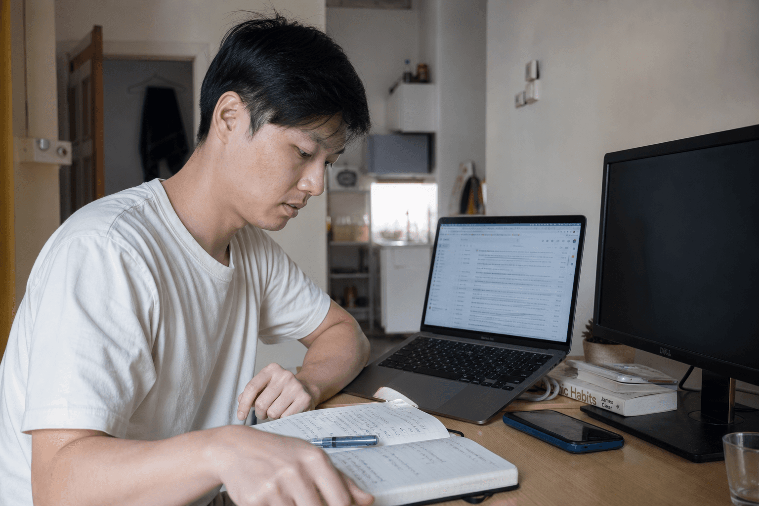 Solo founder comparing a short handwritten outreach list with launch notes on a laptop
