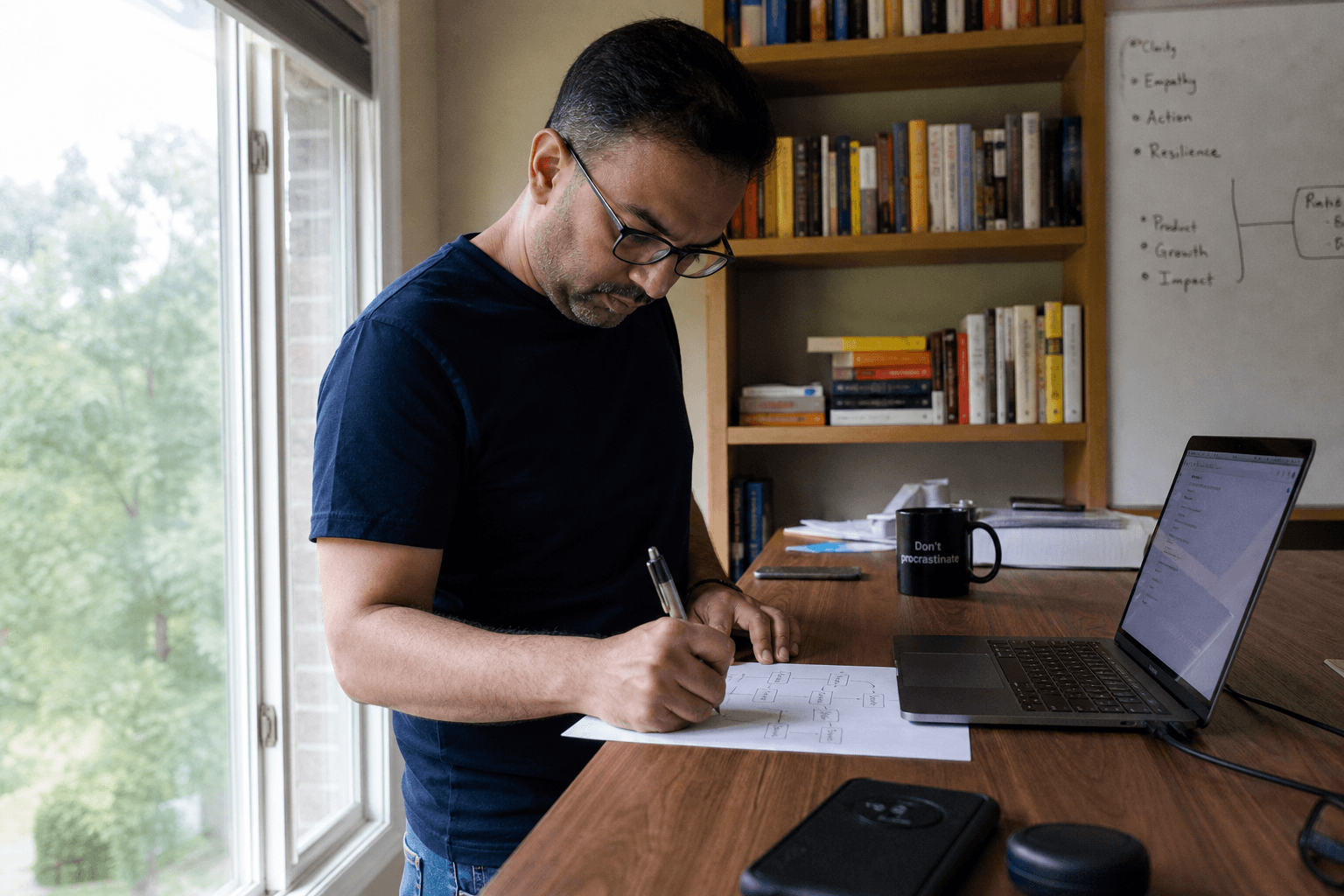 Founder at a standing desk sketching a simple yes-or-no decision tree on paper beside a laptop