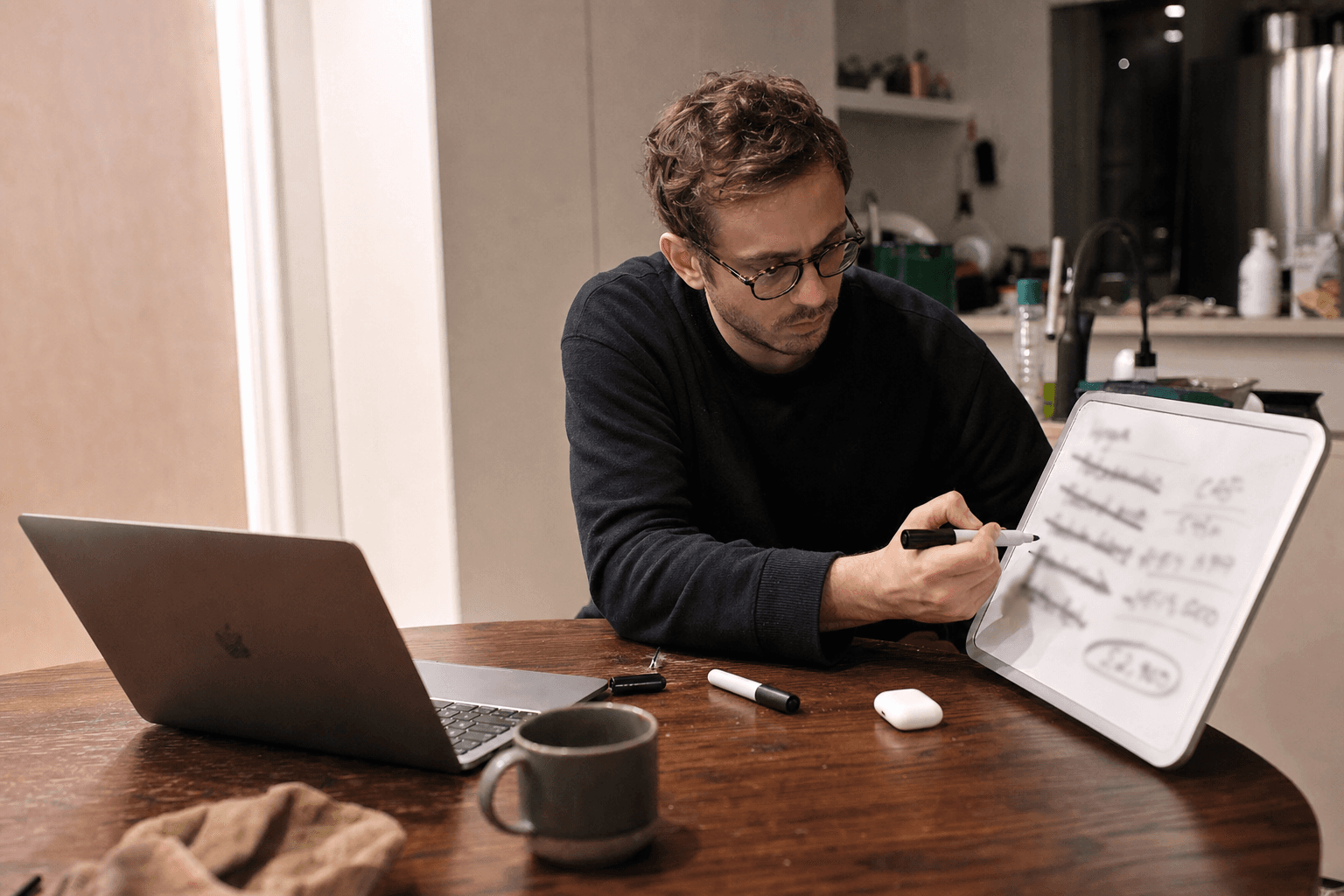 Founder at a kitchen table crossing out vanity metrics on a whiteboard and circling a single revenue number